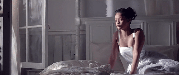 In the first room, Rihanna is in an all-white room, dressed in a white dress.