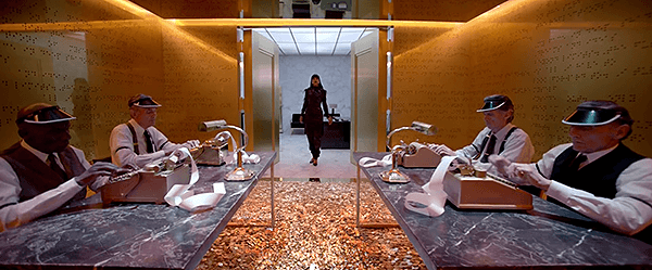 Rihanna opens the heavy doors of a room with walls of gold with braille reliefs (the language of the elite). On the floor, a whole bunch of coins.