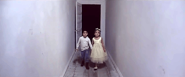 The children (who appear to be twins) walk creeplily backwards towards a black room. 