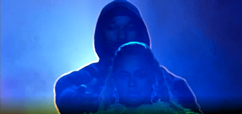 The hooded man brings Beyoncé forward and lets her go, as if saying "This is the path you must take".