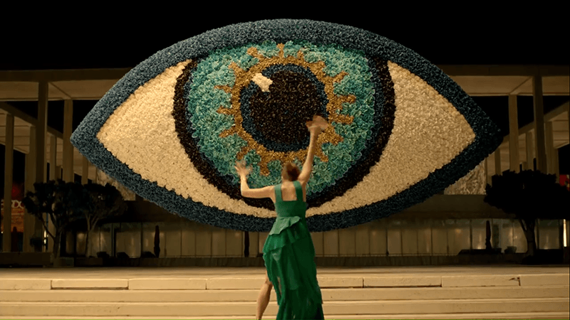 Facing a giant All-Seeing Eye, Margaret wails her arms as if the entity controlling her is forcing her to worship the eye.