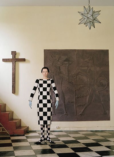 This image is all about the occult concept of duality - which is represented by the checkerboard pattern of Masonic ceremonial floors. The pattern is found on the floor in this picture and Tilda is literally completely draped in it. The setting also includes religious artifacts - symbols giving the Tilda's wardrobe an ethereal meaning.