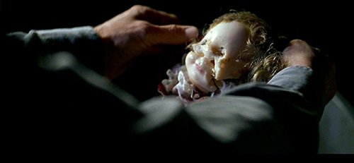 David finds Emily's doll completely defaced in a garbage can. The mutilation represents what the programming in the cave did to Emily's mind. 