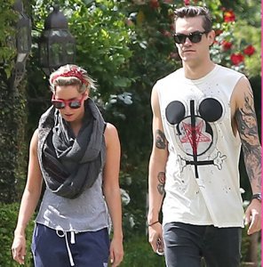 Speaking of former Disney child stars, here's Ashley Tisdale and her boyfriend who is wearing a t-shirt that features a Mickey Mouse head, an inverted cross, the sigil of the Church of Satan and some blood. Is he trying to communicate something through his t-shirt?