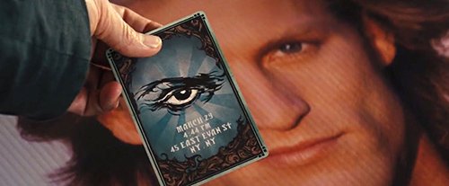 In the back of the card is the symbol of the All-Seeing Eye with invitation information. In this particular shot, the card is hiding one of Merritt McKinney's eyes (played by Woody Harrelson), hinting that he's about to be part of the occult elite's entertainment industry.