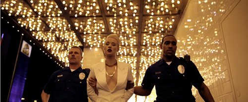 In a scene playing in parallel to the one above, Iggy is shown dressed in white and being arrested by the police. While this might be her being arrested for setting her boss' car on fire, the scene is shown at the same time as the one above and not after it. The scene can represent what happens after initiation in the industry: the "good girl" dresssed in white is taken away while the Illuminati-girl dressed in black (with an All-Seeing eye) stays.