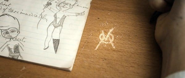 A school boy vandalizes a perfectly good desk with the Viktoria symbol. 