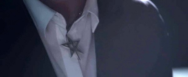The auditioner wears a pentagram with a line going through it. It is the symbol revealed by the good people at the production company.