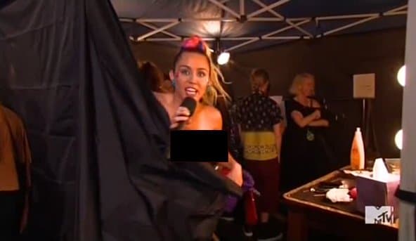 Later during the show, we see Cyrus apparently naked behind a curtain presenting something. The camera then cuts away because her boob is out. We then hear Miley says "My tit is out?"